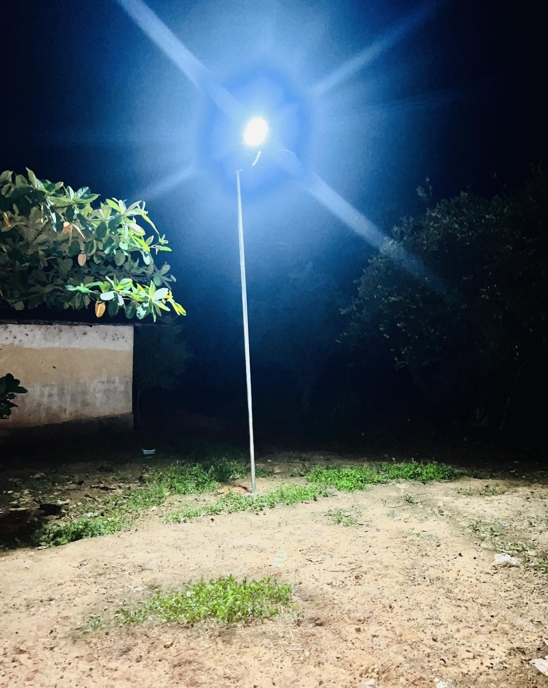 A solar street light lit at dusk in a village