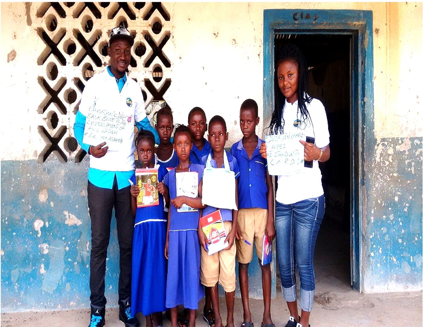 A CARDO volunteer and pupils holding certificates at a school doorway
