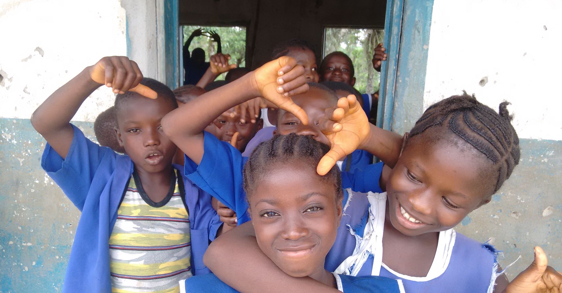 Smiling girls in blue school uniforms peering through a doorway