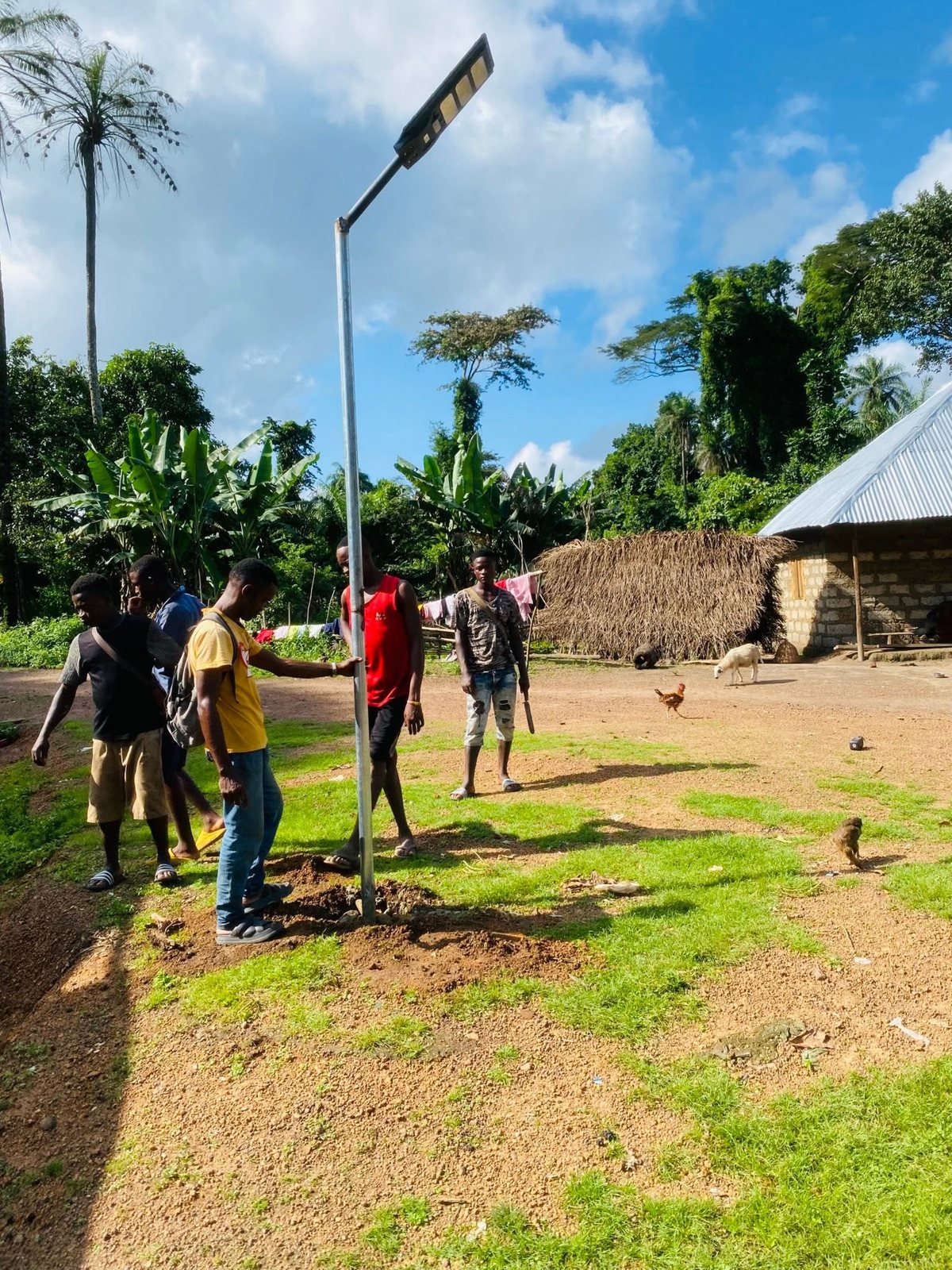 Young men installing a solar street light pole in a village