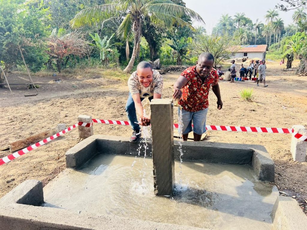 Two men washing their hands at a new water point marked with red-and-white tape