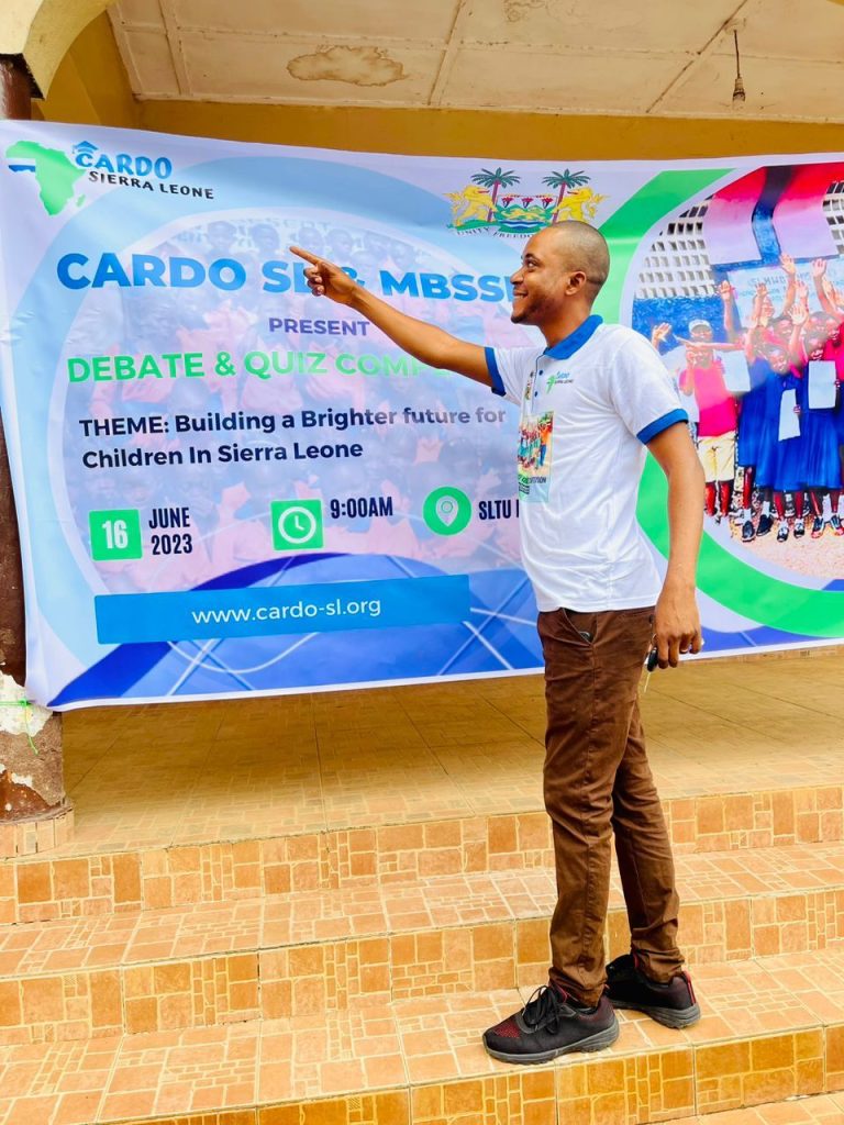 CARDO's founder speaking in front of the Debate and Quiz Competition banner