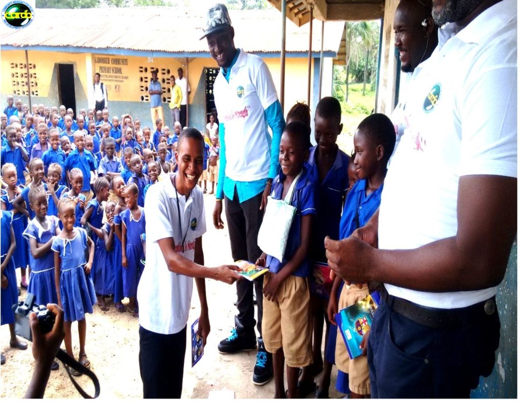 CARDO volunteer with a pupil holding a certificate during a school materials donation near Makeni
