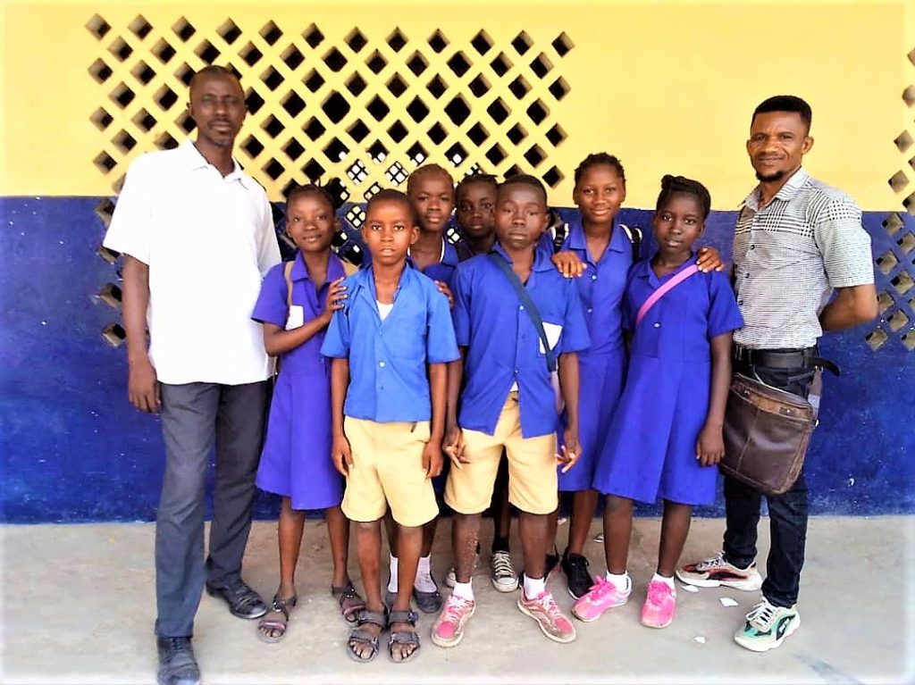 Adults with pupils in school uniform outside a school building