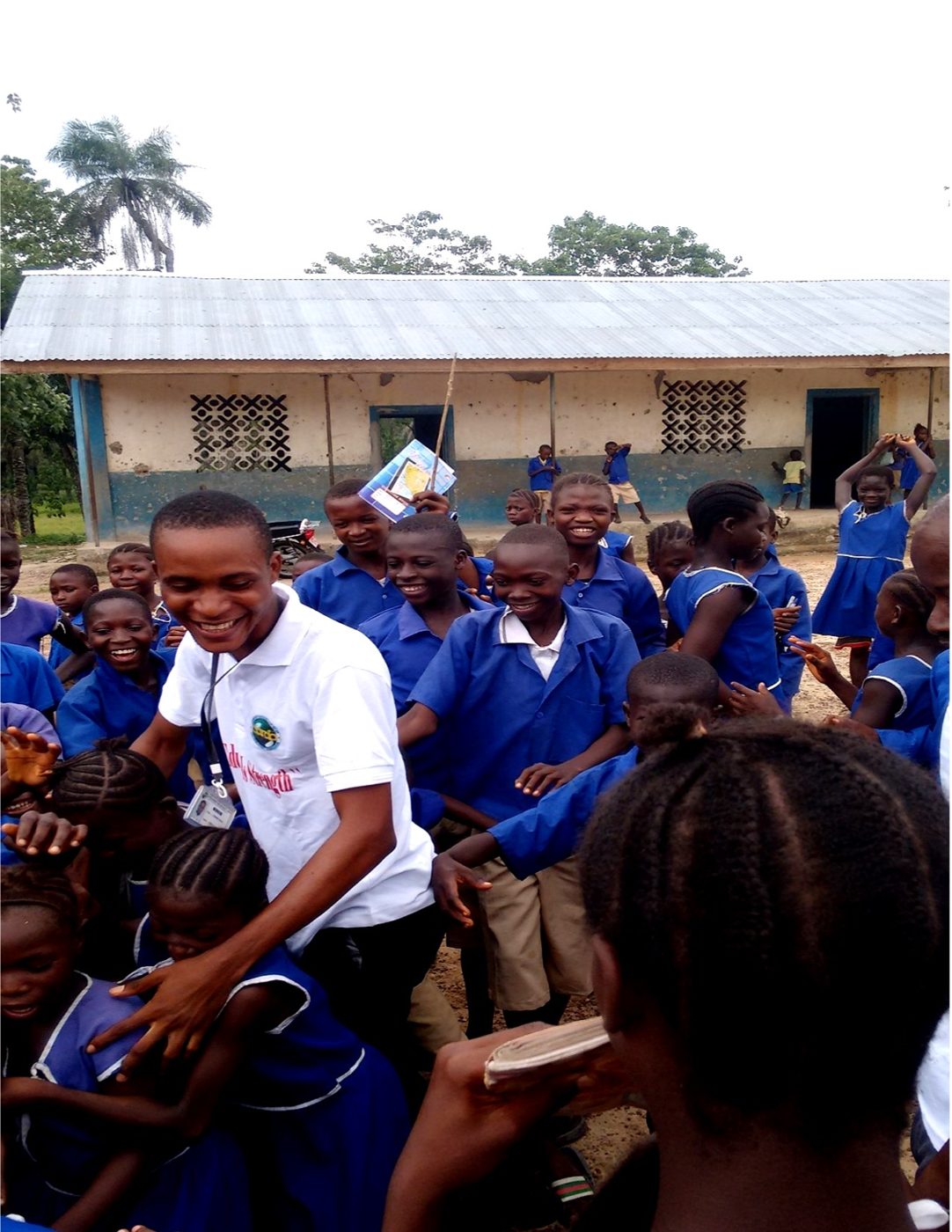 A large group of pupils gathered as an adult distributes items