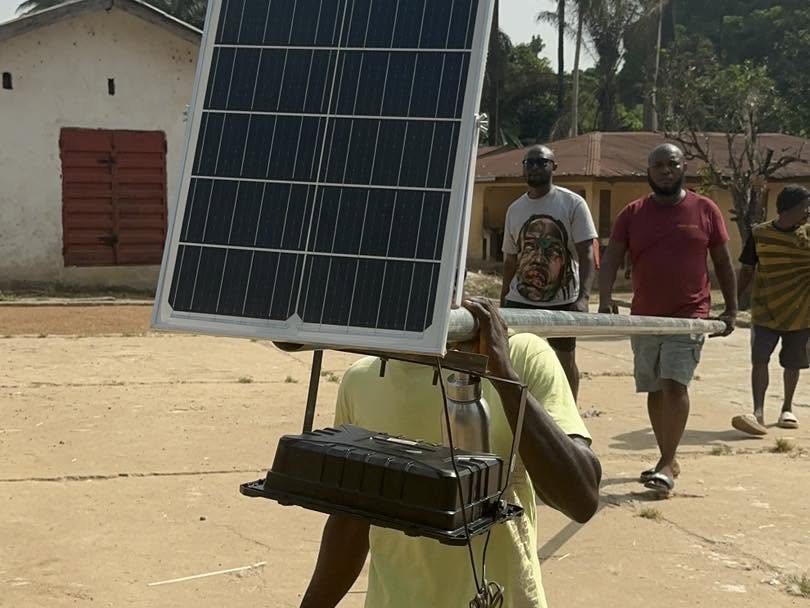 A CARDO team member carrying a solar street light panel and battery
